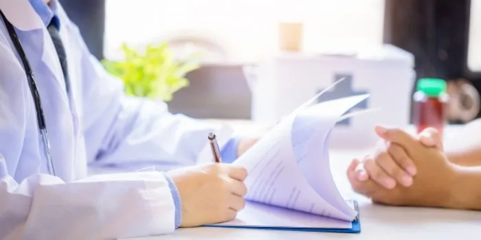 A clinician taking notes on a clipboard across from a patient