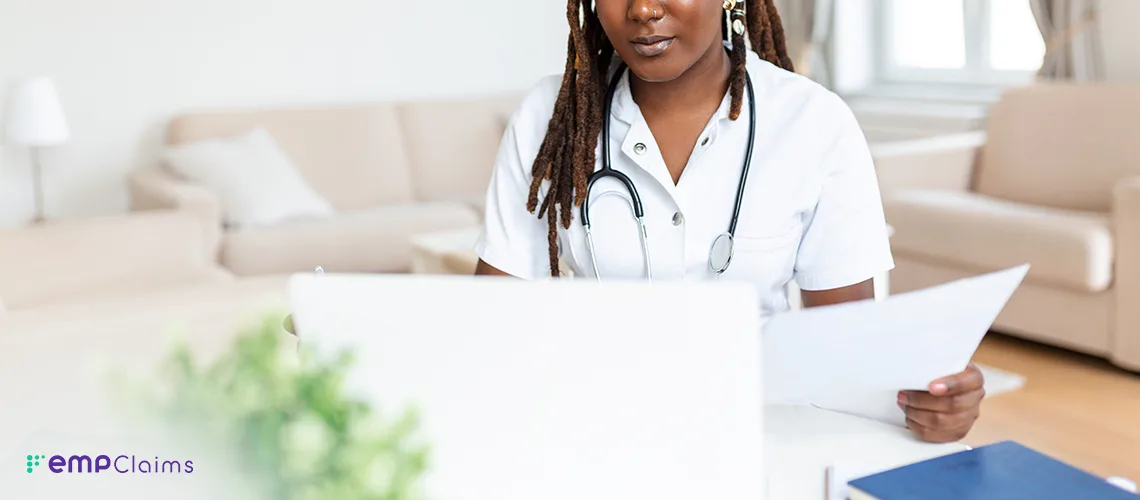 A clinician reviewing authorization paperwork at a laptop