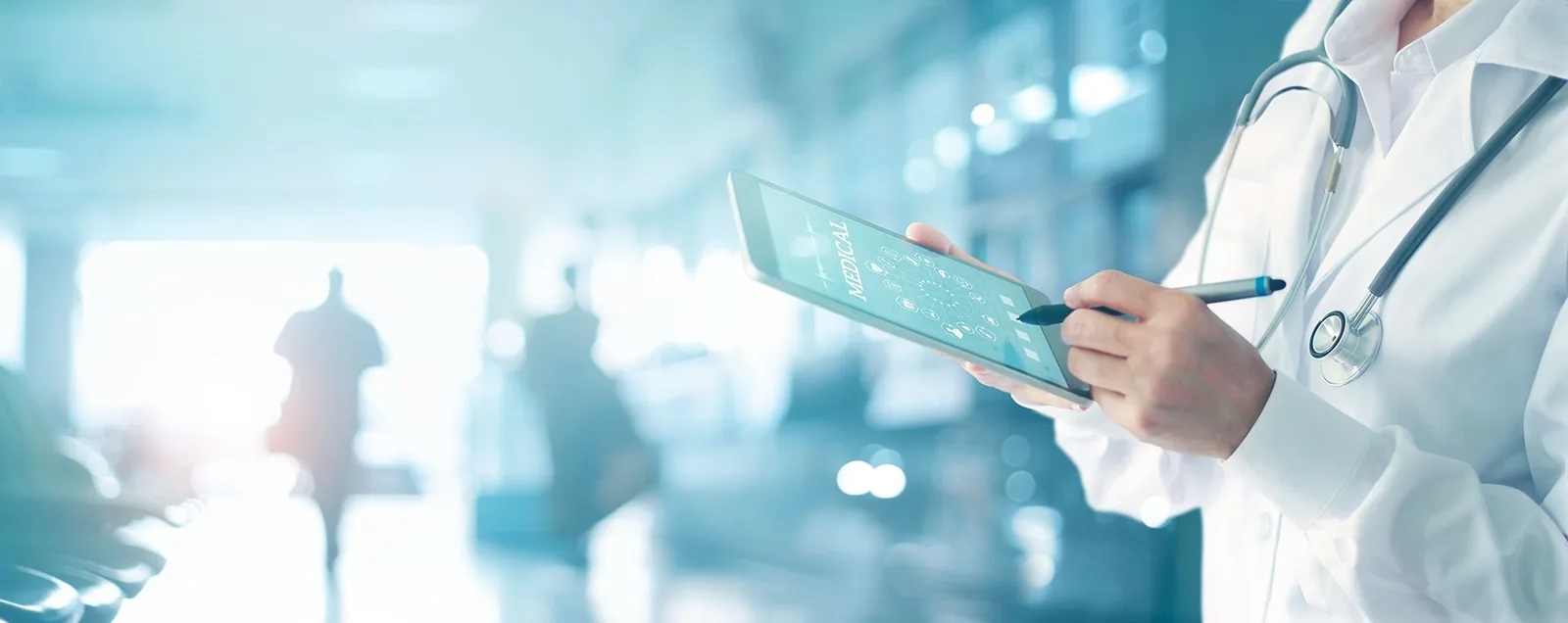 A clinician reviewing a tablet in a hospital corridor