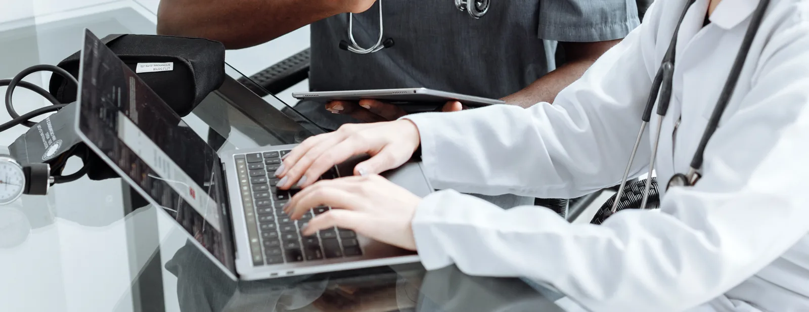 Two clinicians reviewing credentialing paperwork together at a laptop