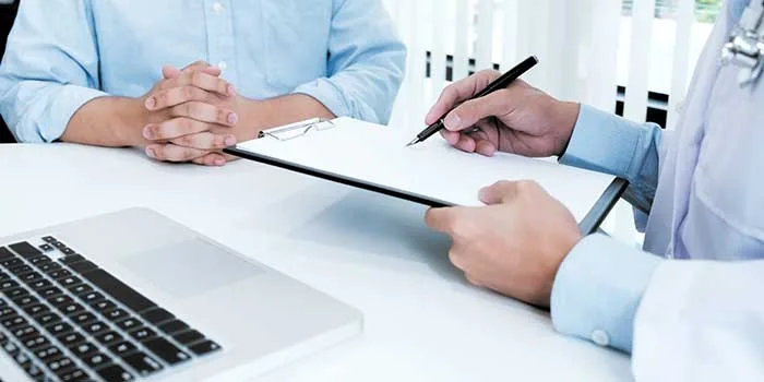 A clinician going over paperwork with a patient across a desk