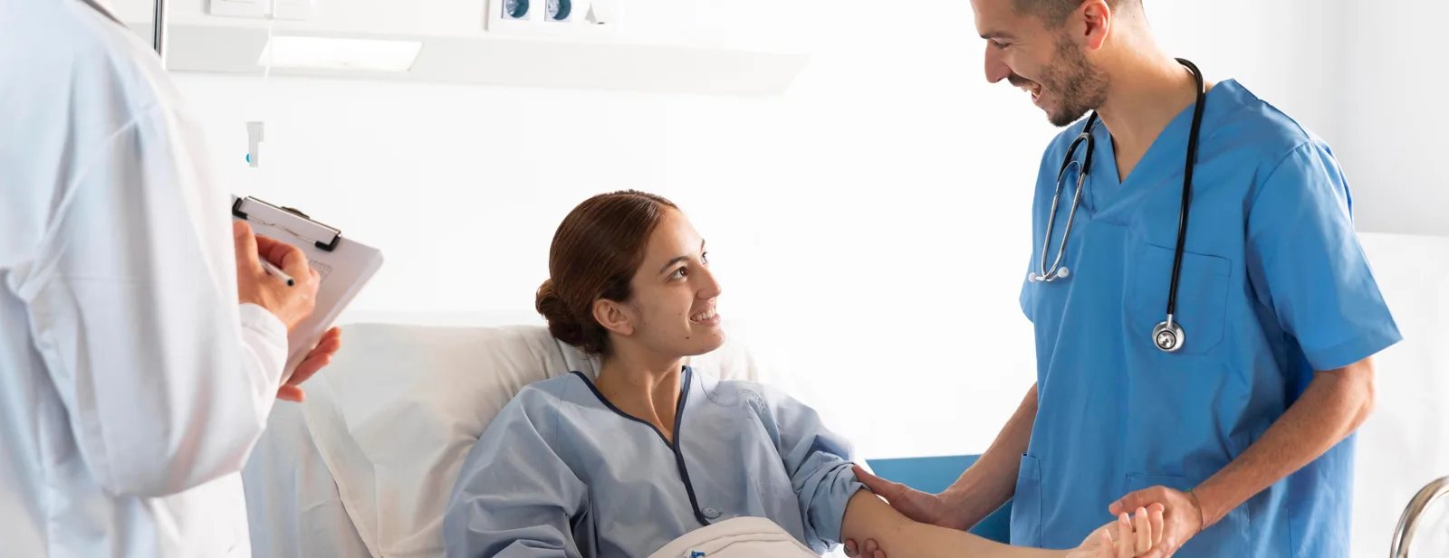 A nurse and a clinician talking with a patient at the bedside