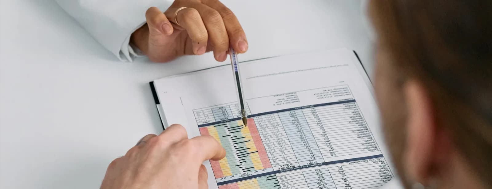A person reviewing a printed remittance report with a pen