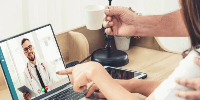 A patient meeting with a doctor over a video call on a laptop